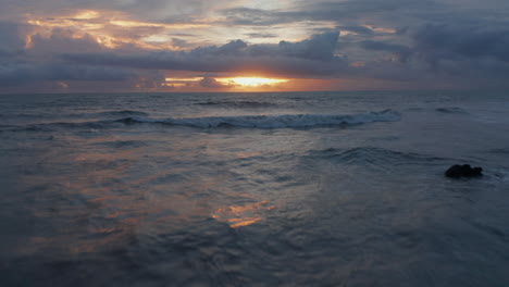 Low-aerial-shot-of-rough-sea-waves--during-golden-sunset-in-Bali.-Point-of-view-of-ocean-waves-crashing-ashore-in-beautiful-warm-evening-light