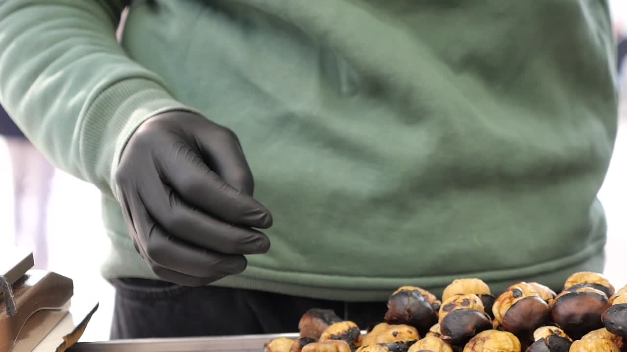 Close-Up of Hands in Gloves Peeling a Roasted Chestnut