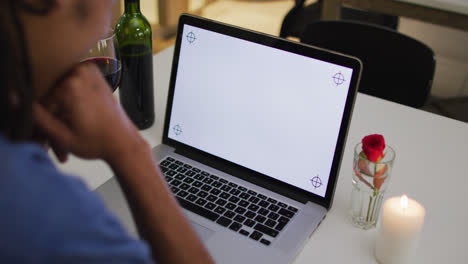 Mixed-race-man-having-a-romantic-dinner-on-video-chat-using-laptop-with-copy-space