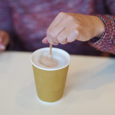 woman adding sugar and mixing coffee in cafe. coffee break in cafe. hot drink in paper cup