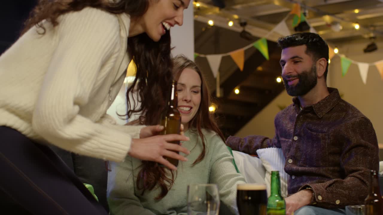 grupo de amigos en casa o en un bar celebrando en la fiesta del día de san patricio haciendo aclamaciones con alcohol y comiendo palomitas de maíz