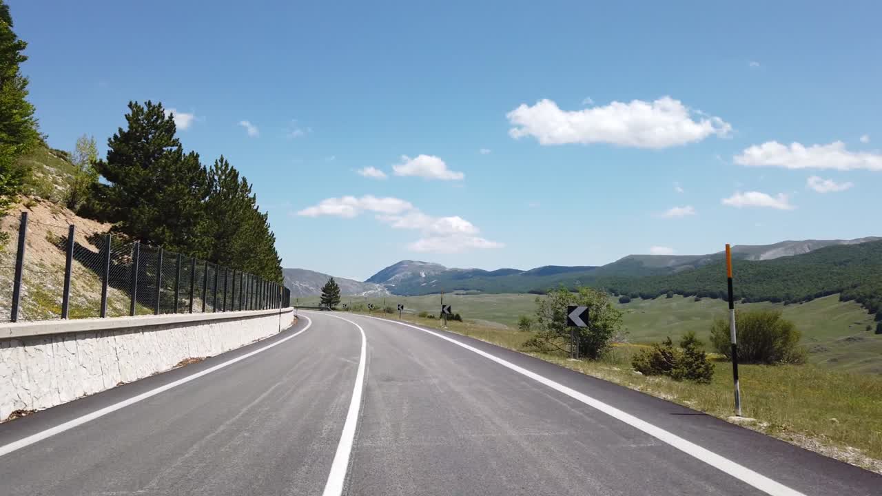 Veduta in movimento (auto, moto o bicicletta) di un paesaggio montano