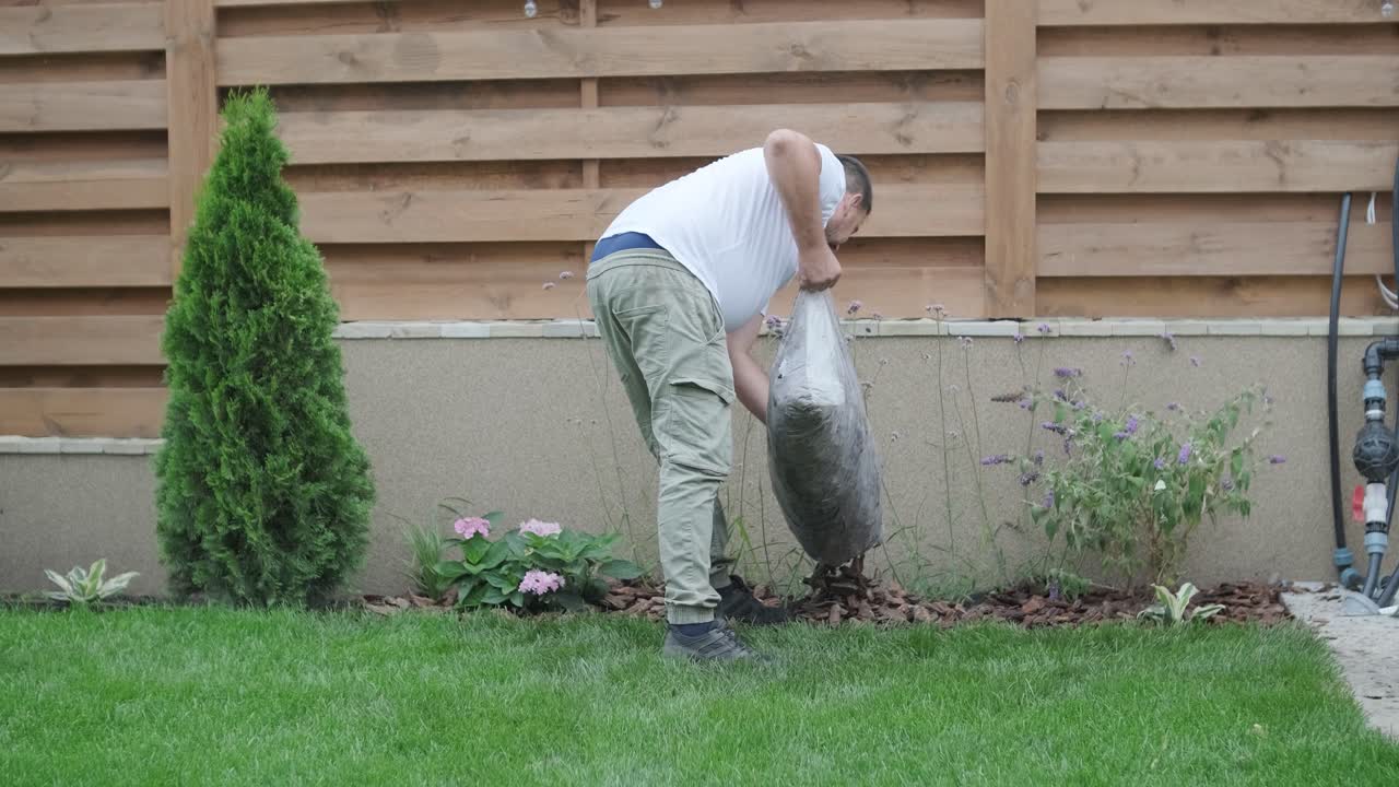 Gardener Applying Mulch Around Plants in Backyard Garden for Landscaping
