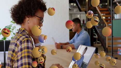 group of emoji icons flowing over woman using laptop.