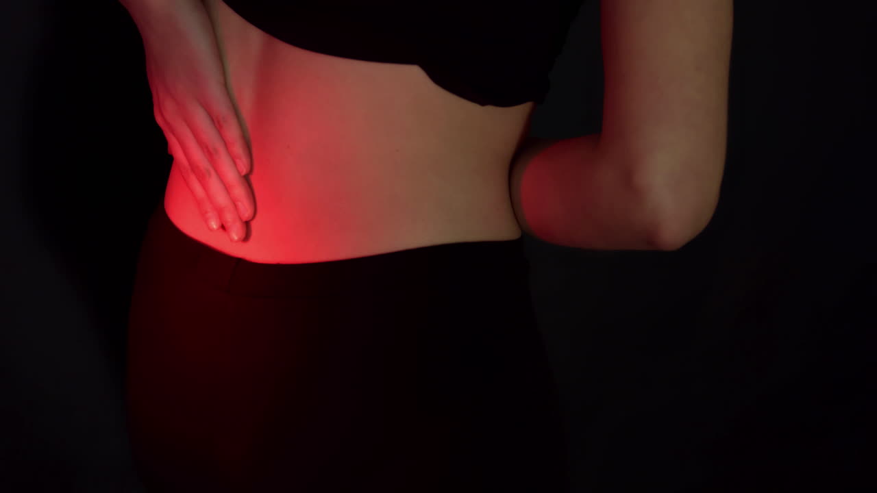 Woman with backache pain grabing back during heat therapy,static