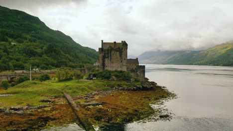 Langsamer-Vorbeiflug-An-Eilean-Donan-Castle,-Mit-Schottischer-Flagge,-Drohnen-Luftvideo-In-4K