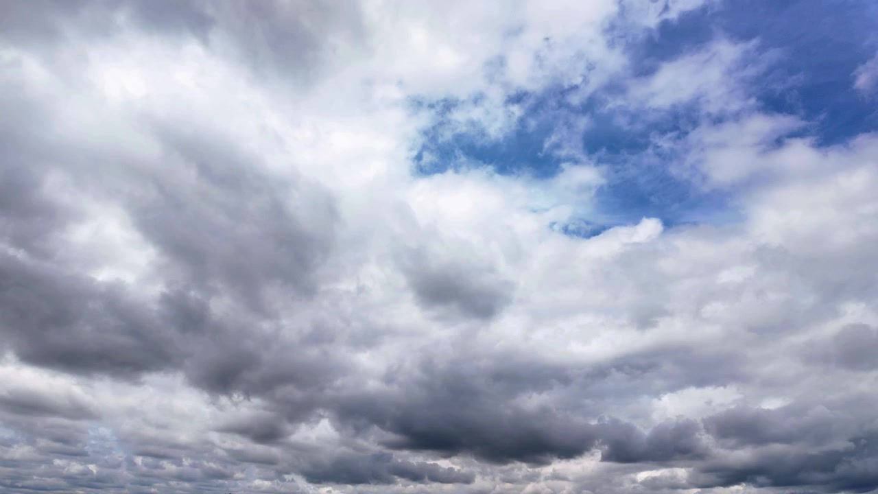 A dynamic timelapse of dark, dramatic gray clouds moving across a bright blue sky, creating a powerful and atmospheric scene.
