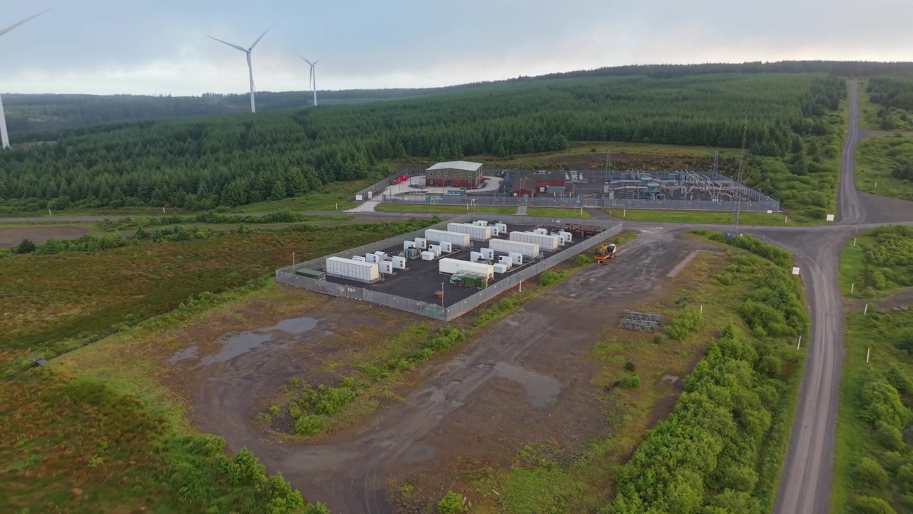 Retreating Aerial of BESS Battery Energy Storage System Facility with Substation at Wind Farm.