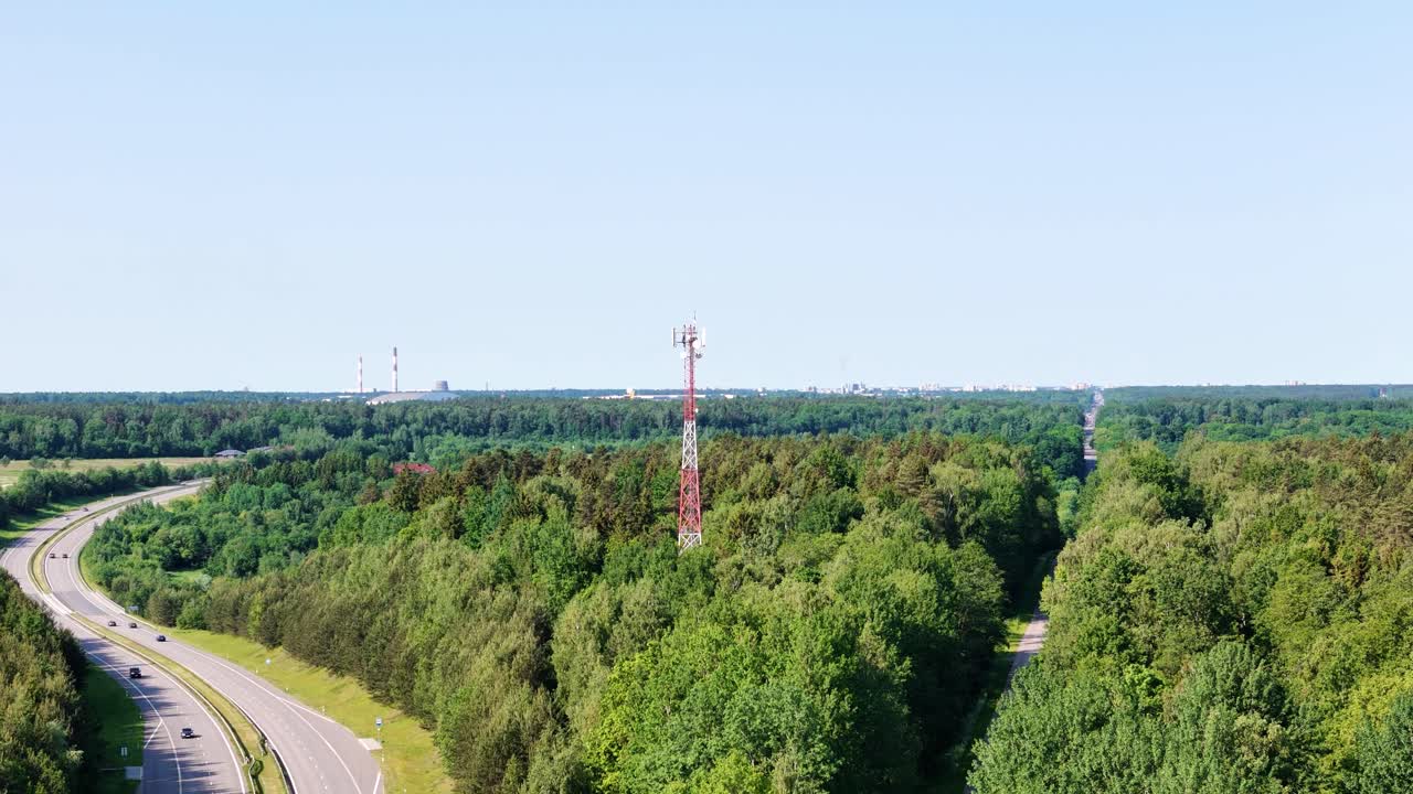 Winding highway, forest and cell tower, aerial fly forward view