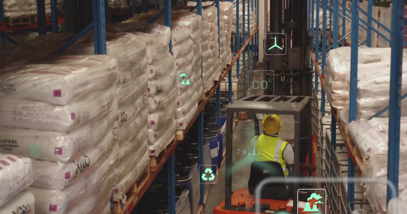 Reacting to sensor overlays, driver in hi-vis hard hat aligning forks to lift pallet in warehouse
