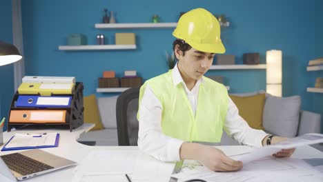 Funny-boy-working-at-his-desk-wearing-engineering-clothes-and-hard-hat.