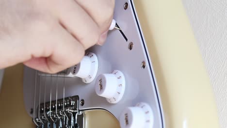 Una-Mano-Que-Mueve-El-Interruptor-De-Recogida-De-Una-Guitarra-Eléctrica-Stratocaster-Blanca-Crema