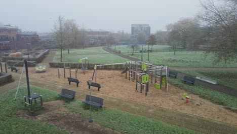 Luftaufnahme-Eines-Wunderschönen-Grünen-Parks-In-Einem-Vorstadtviertel-An-Einem-Kalten-Und-Nebligen-Morgen