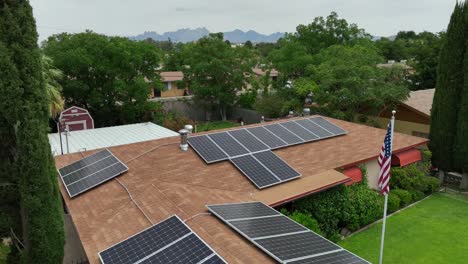 vista de un avión no tripulado de una casa suburbana con paneles solares, con un telón de fondo, vegetación exuberante y montañas lejanas en el suroeste de los estados unidos