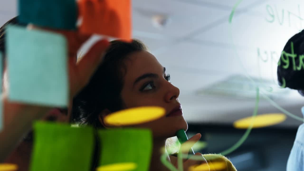 Executives discussing over sticky notes on glass wall