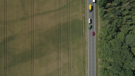 Faszinierender-Blick-Von-Oben-Auf-Pendler-Auf-Einer-Straße-Zwischen-Feldern-Und-Wald