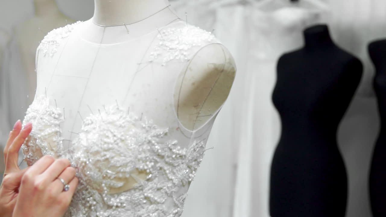 그의 스튜디오에서 신부들을 위한 클로즈업 패션 디자이너, 핀, 바늘, 레이스 웨딩 드레스. 바느질은 독점적인 웨딩 드레스를 만 ⁇ 니다. 핀과 바늘의 윤 ⁇ 으로 안전합니다. 작은 개인 사업