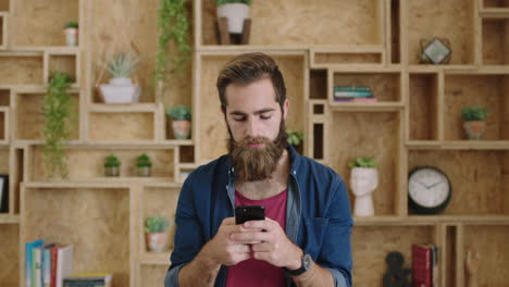 portrait of handsome young hipster businessman with beautiful beard texting browsing using smartphone smiling cheerful