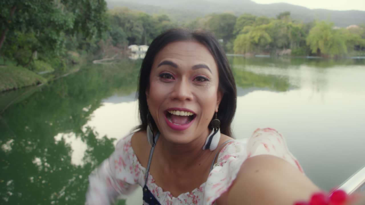 Woman taking a selfie by a lake in a park