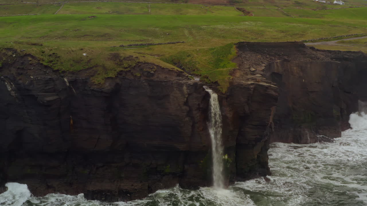 Close aerial view of Cliffs of Moher waterfall at Doolin plunging into Atlantic Ocean
