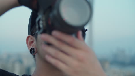 close up on a young asian photographer capturing skyline reflected in his sunglasses from the rooftop in the early morning