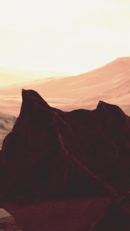 a large rock in a desert landscape with a mountain in the background