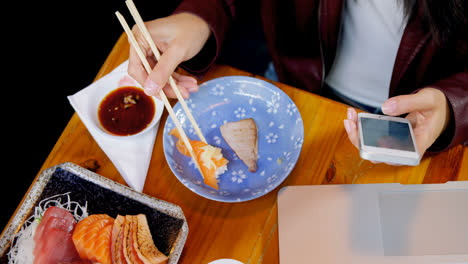 Woman-having-sushi-while-using-mobile-phone-in-restaurant-4k