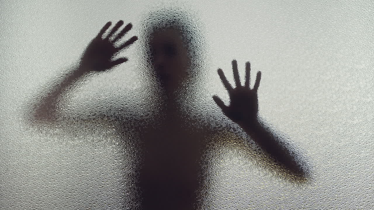 A female silhouette behind the frosted window slowly touches the glass