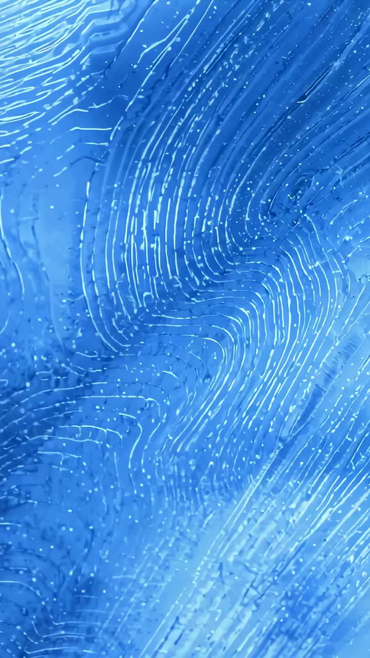 Vertical video: Moving light band nudging blue textured surface forming swirls macro, showing depth