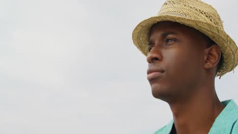 Side-view-of-African-American-man-in-hat-standing-on-the-beach-4k