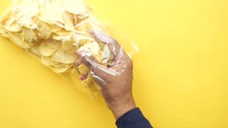 mano metiendo la mano en una bolsa de papas fritas