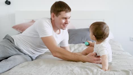 un padre cariñoso está jugando con su pequeño hijo y acariciando su cabeza en el dormitorio en las vacaciones