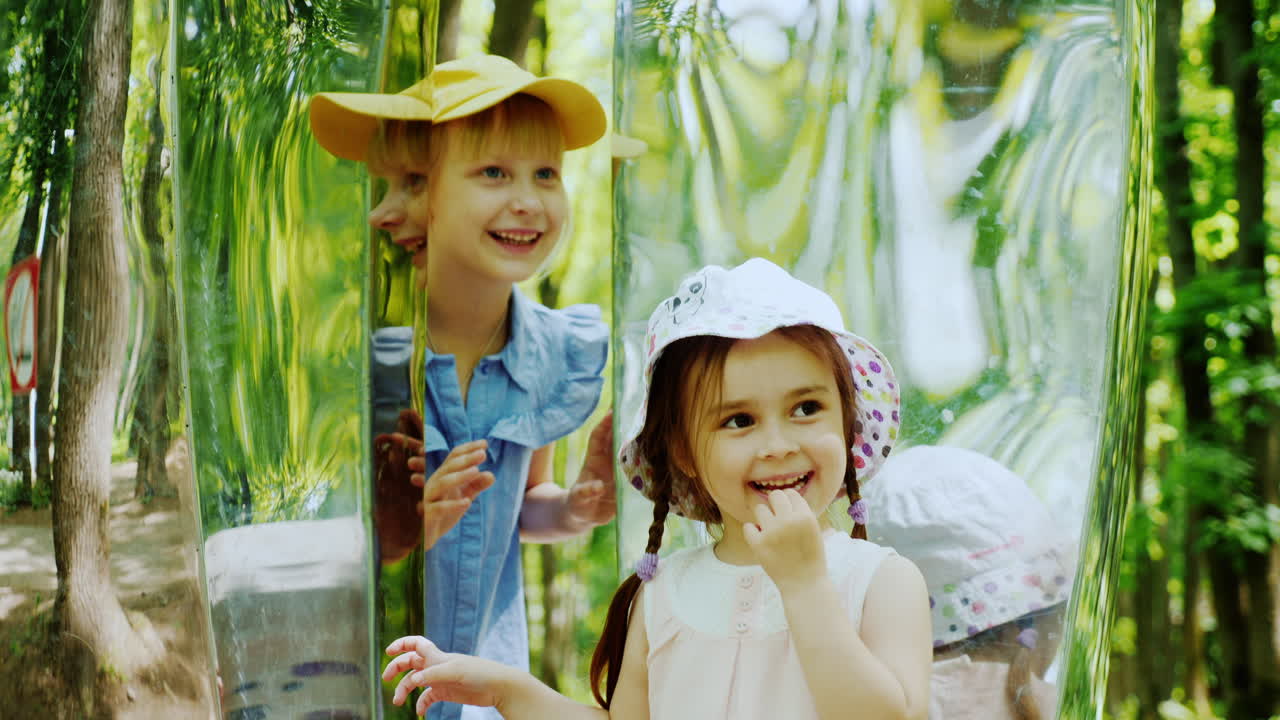 dos niños mirándose en un espejo torcido riéndose