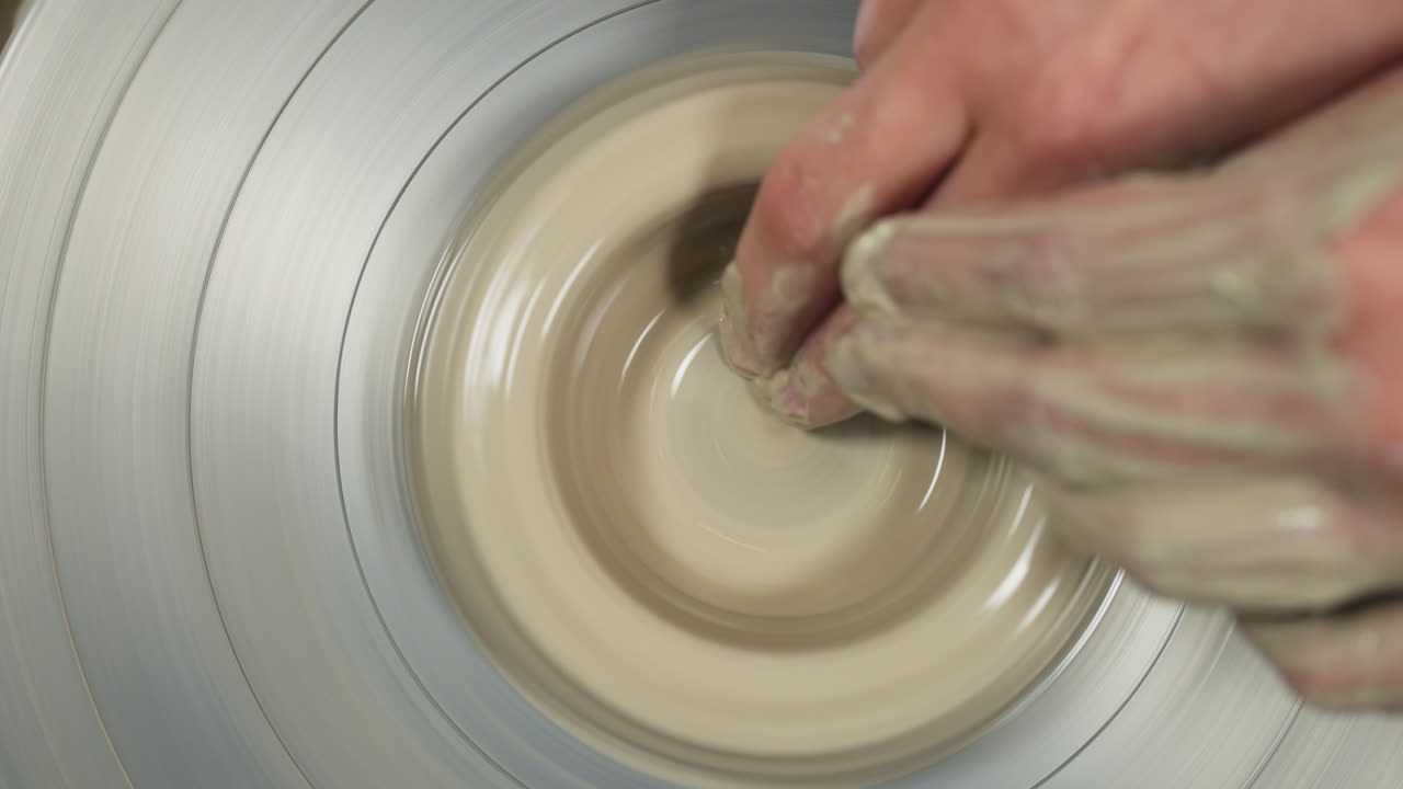 Top shot of white hands making mug from clay, interior