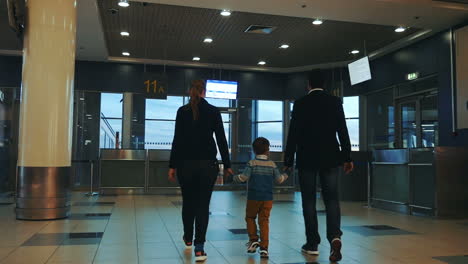 family of three walking in airport terminal