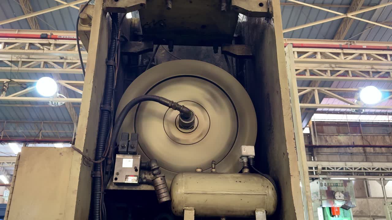 Spinning industrial equipment component with visible hoses and connections, illustrating mechanical rotation and power transmission in a manufacturing process