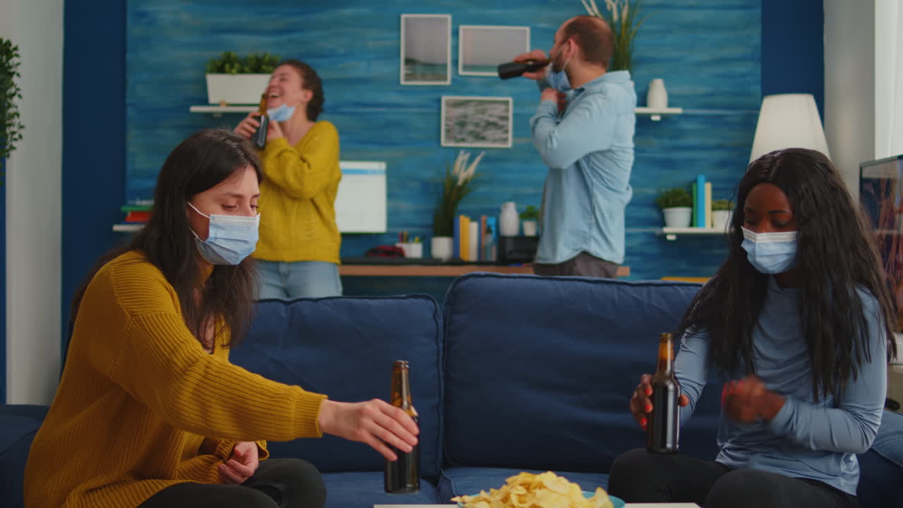 Mixed race black woman taking off protection masks clinking bottles of beer