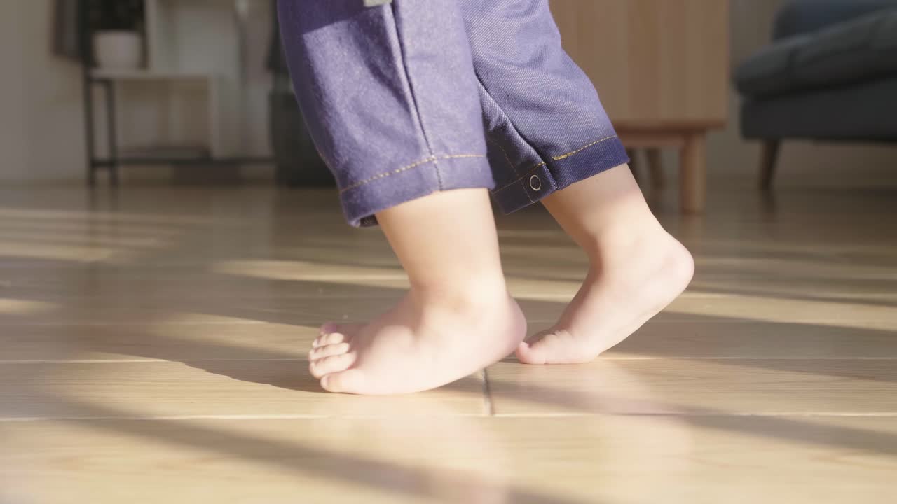 Baby Boy Learning To Walk And Make His First Steps. Father Is Holding His Hand. Child'S Feet Close Up