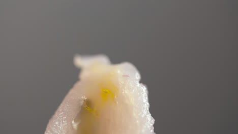 extreme nahaufnahme von olivenölstropfen in zeitlupe auf einem weißen fischfilet in einem ceviche-gericht mit grauem hintergrund - ein buntes und gesundes gericht der kulinarischen kultur verschiedener spanisch-amerikanischer länder