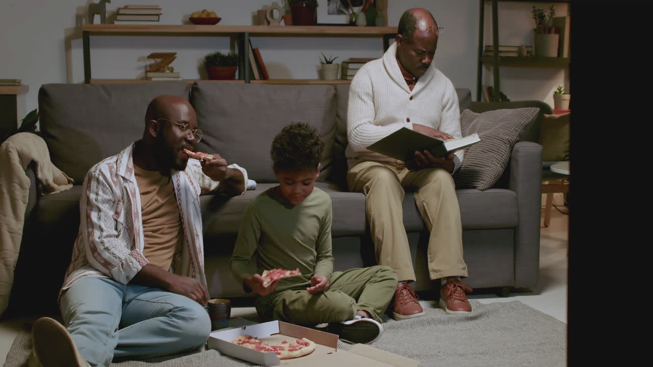 Black men and boy in the living room at night