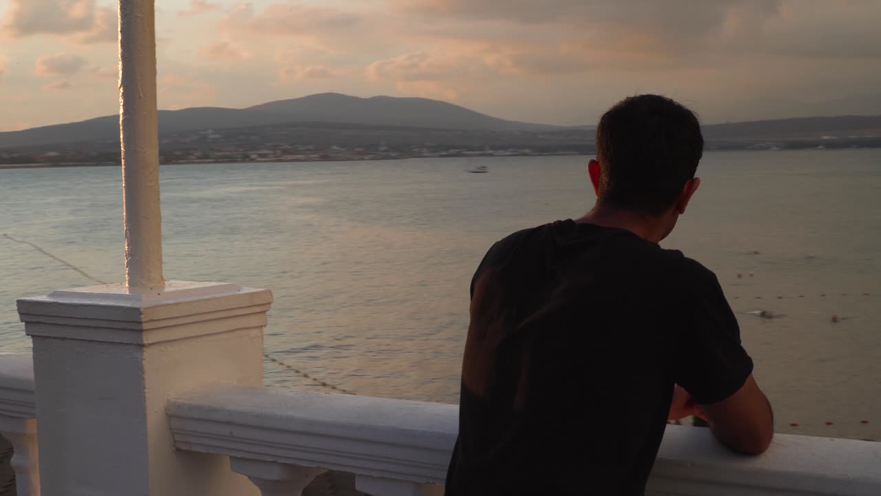 발코니 에서 바다 위 에 해 가 지는 것 을 지켜보는 사람