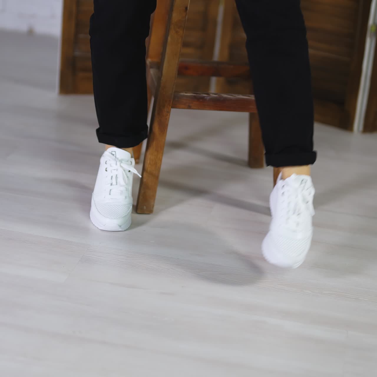 Model jumping in comfortable white sneakers. Woman spinning and hopping to demonstrate fashionable sport footwear