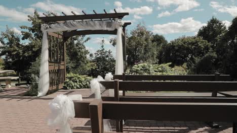 beautiful outdoor wedding venue, panning shot filmed from the seating benches of a beautiful archway with stunning blue cloudy skies and a gorgeous garden behind it