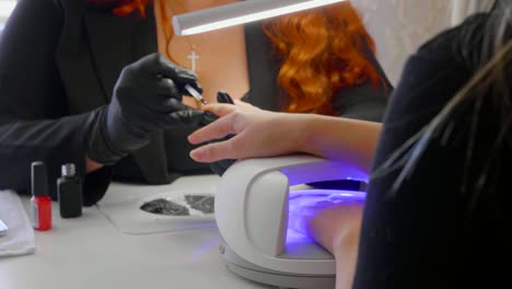la mujer roja hace un procedimiento de spa para las uñas del cliente