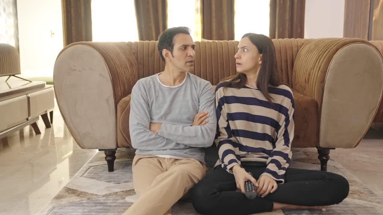 una pareja india ve una noticia impactante en la televisión.