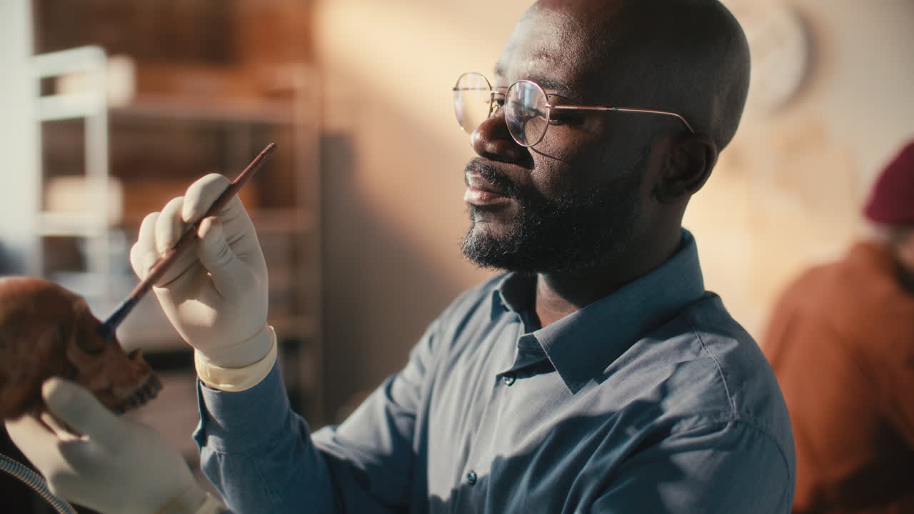 Black Archaeologist Brushing Human Skull during Laboratory Research