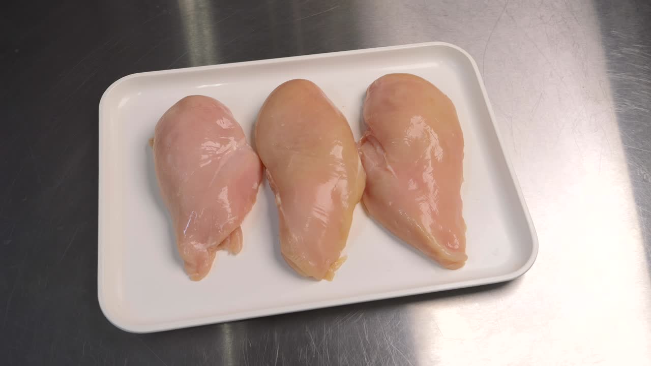 primer plano de filetes de pollo frescos en una bandeja, listos para su posterior procesamiento