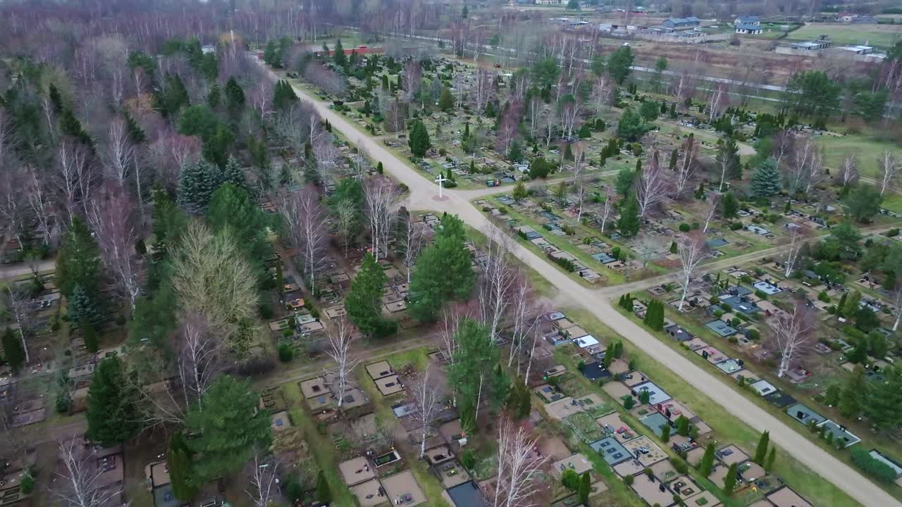 Drone footage showing rows of graves near road in overcast weather conditions