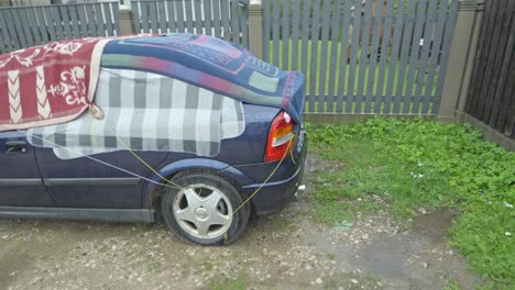 covering car with thick cloth to protect from hail on rainy day