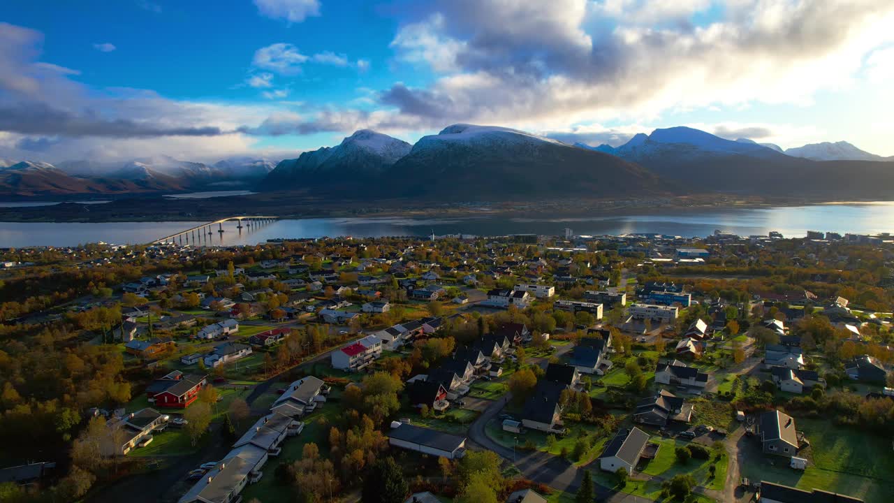 Dramatic aerial drone shot from a small town of Sortland on a sunny day during autumn with snow covered mountains